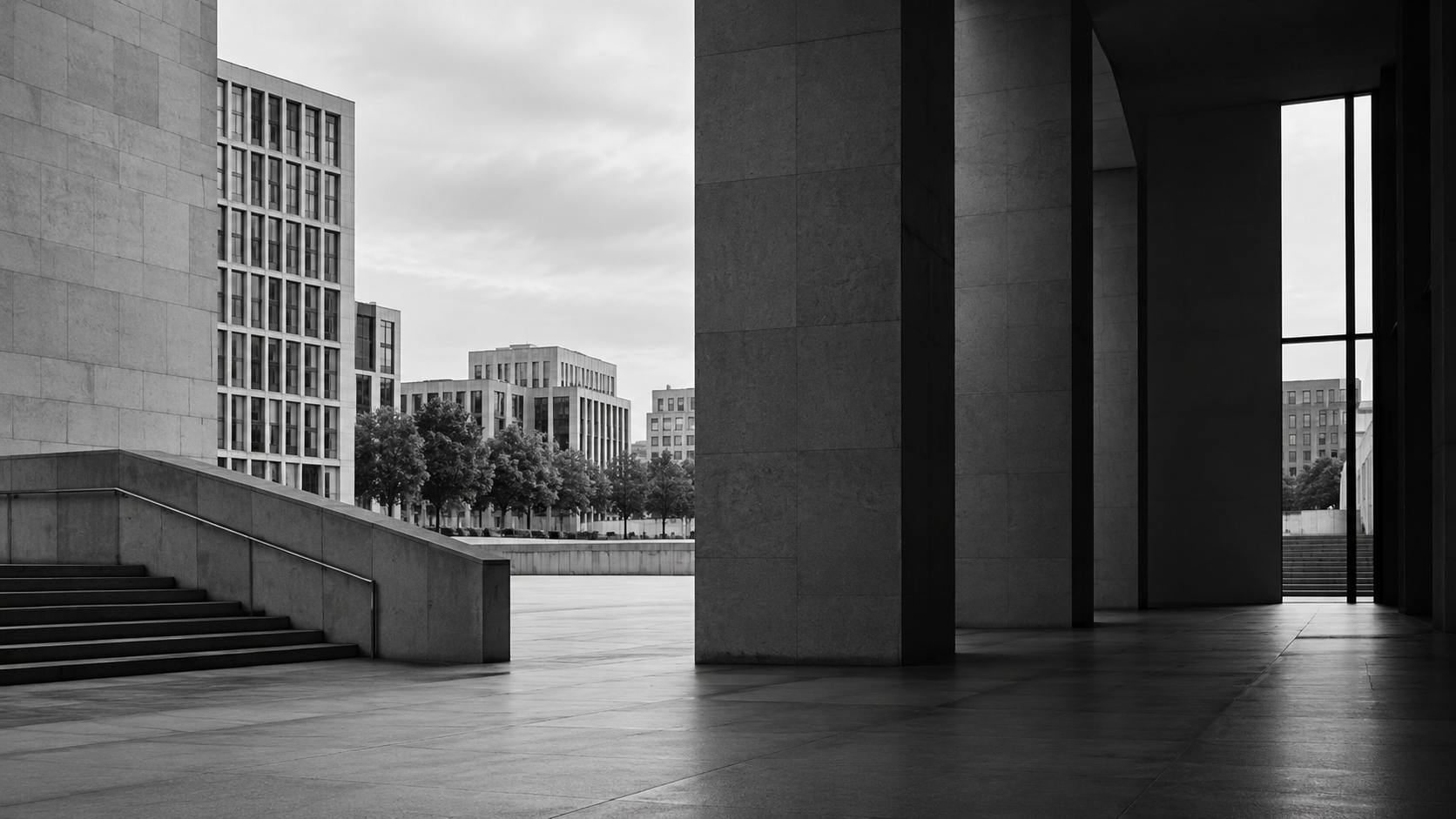 A black-and-white view through a civic passage toward a city square